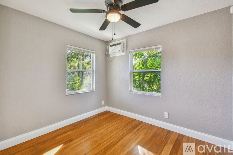 A room with a ceiling fan and two windows.