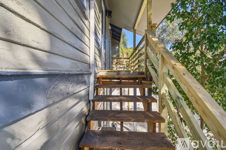 A wooden staircase with a railing leads up to a doorway.