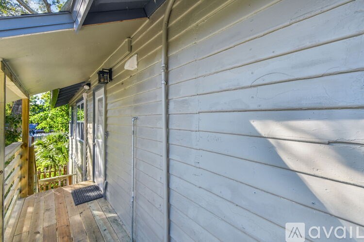 A wooden deck with a metal grate is attached to a white siding building.