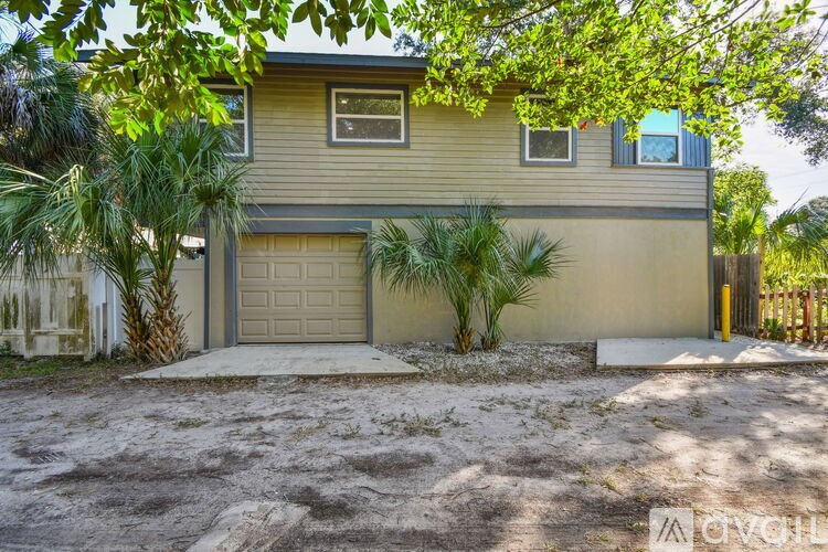 A house with a garage and a driveway surrounded by trees.