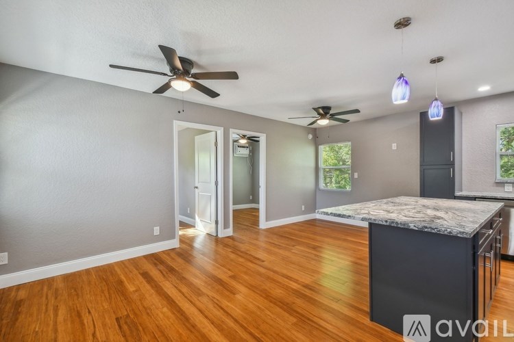 A room with a ceiling fan and a kitchen island.