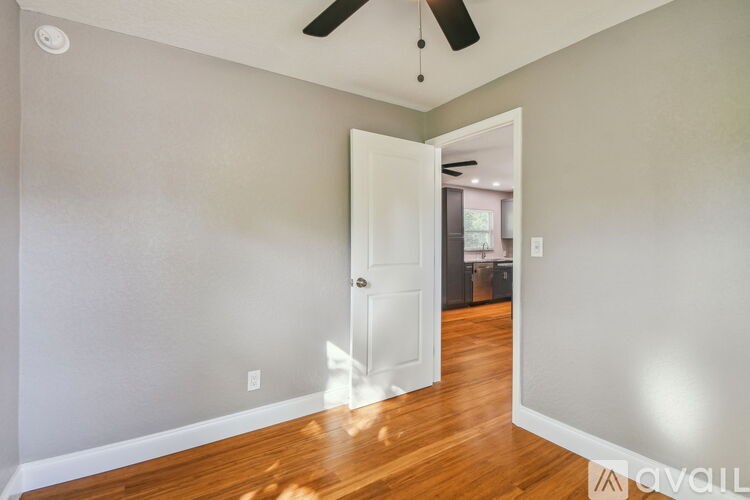 A room with a white door and a ceiling fan.
