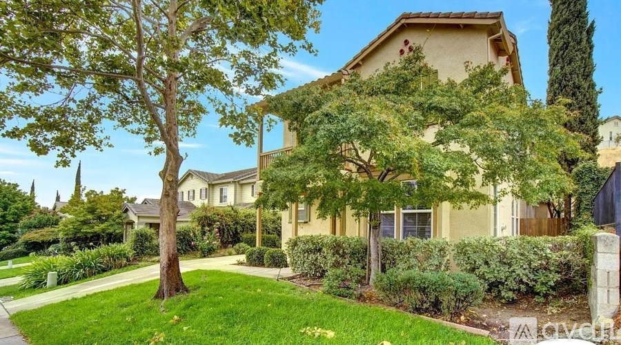 A house with a well-maintained lawn and trees in front.