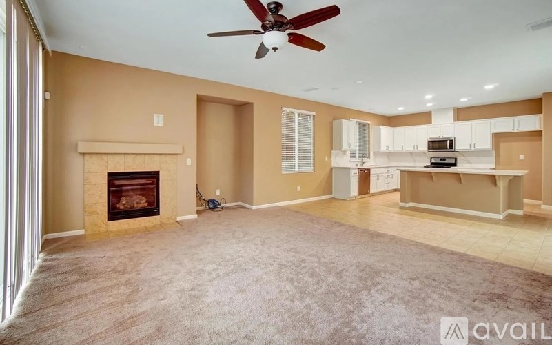 A spacious living room with a fireplace and a fan.