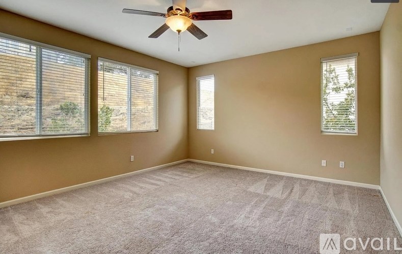 A room with a ceiling fan and carpeted floor.