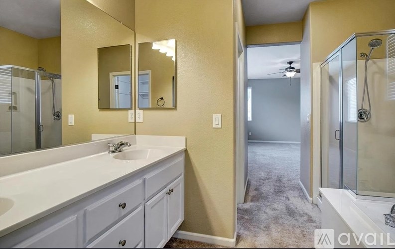 A bathroom with a sink, mirror, and shower.