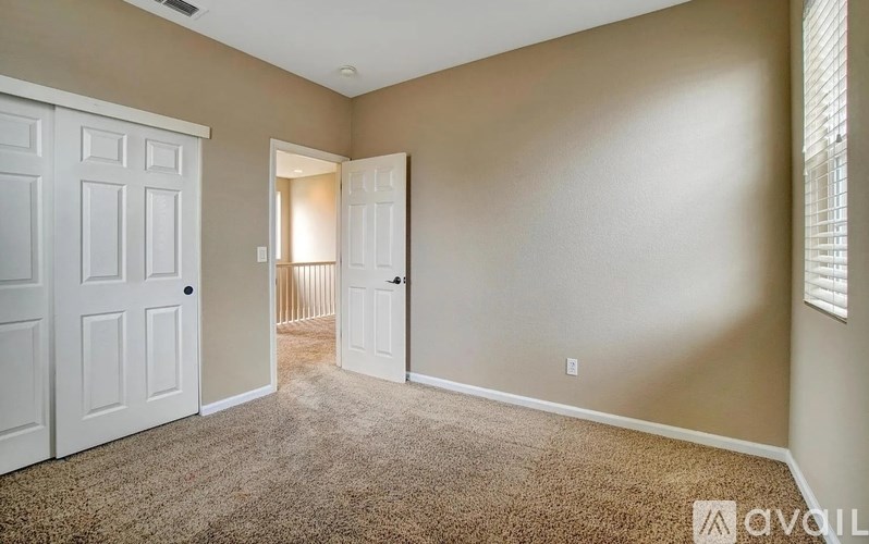 A room with a carpeted floor and two white doors.