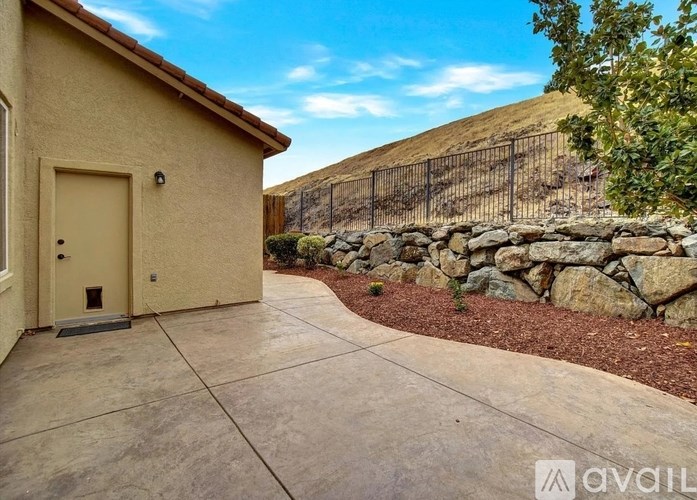 A house with a stone wall and a brown door is for sale.