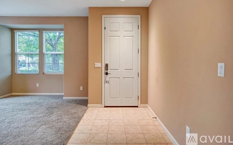 A room with a white door and a carpeted floor.