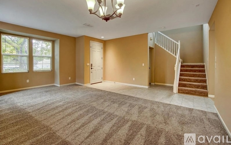 A spacious room with a staircase and a chandelier.