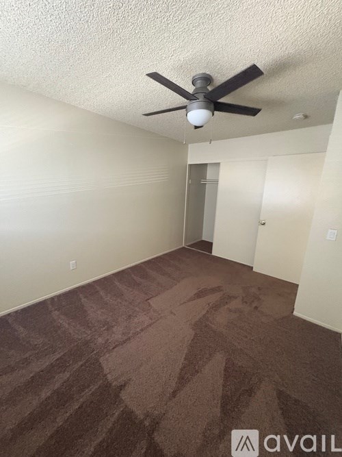 A room with a ceiling fan and carpeted floor.