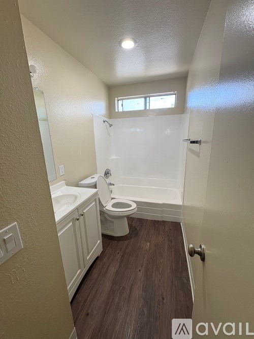 A small bathroom with a toilet, sink, and wooden floor.