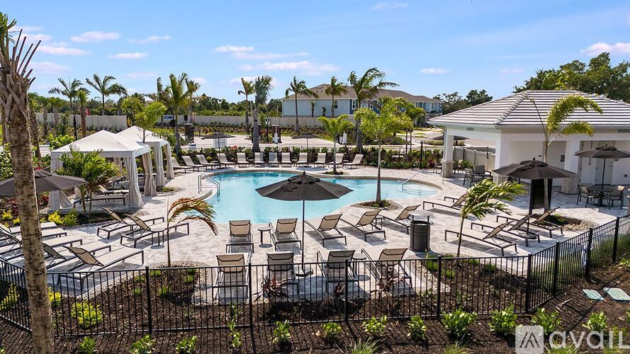 A pool surrounded by chairs and umbrellas with a house in the background.