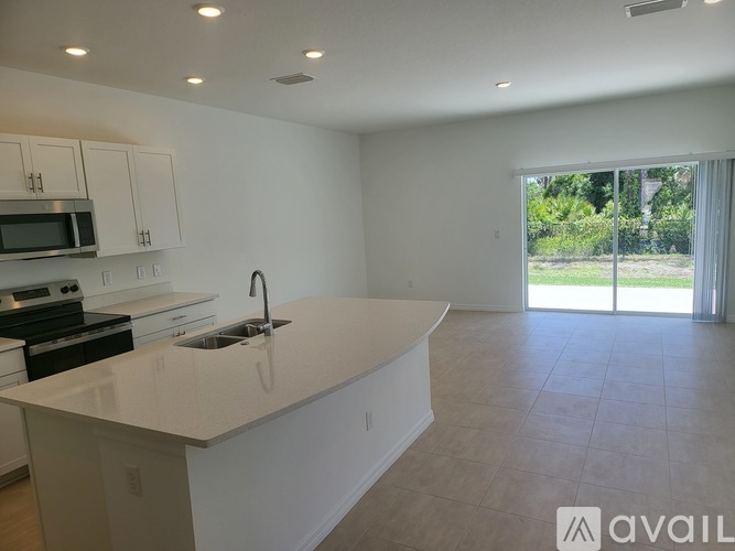 A kitchen with white cabinets and a large island with a sink.