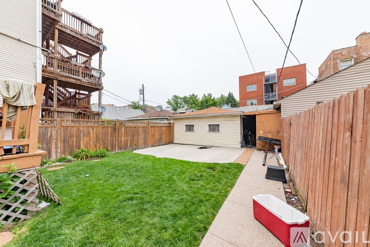 A backyard with a wooden fence and a red cooler.