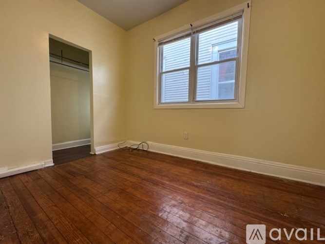 A room with wooden floors and a window with blinds.