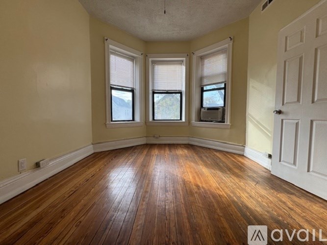 A room with wooden floors and three windows.