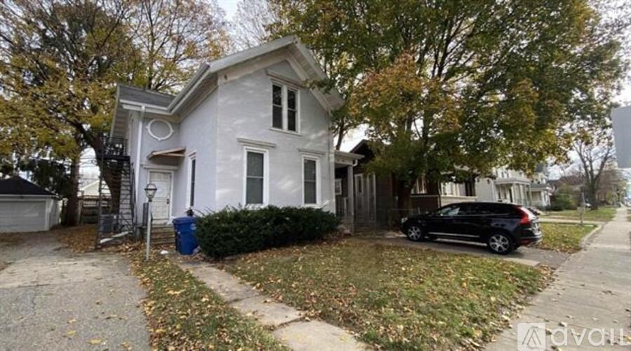 A white house with a black car parked in front.