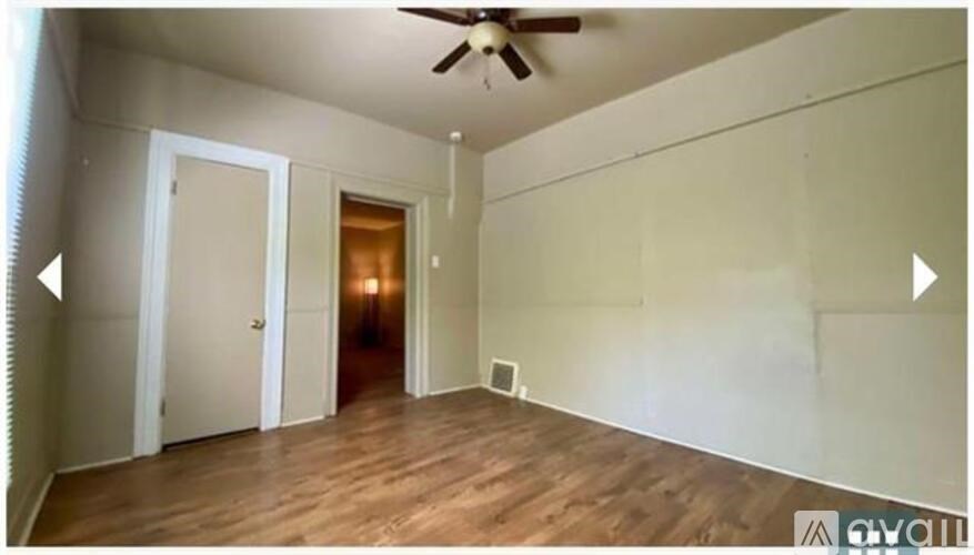 A room with a ceiling fan and wooden flooring.