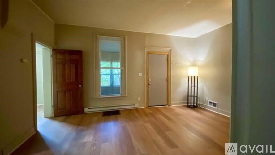 A room with wooden floors and a window with a view of trees.