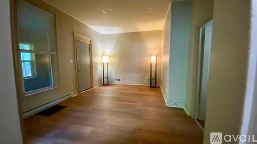A long hallway with wooden floors and two wall sconces.