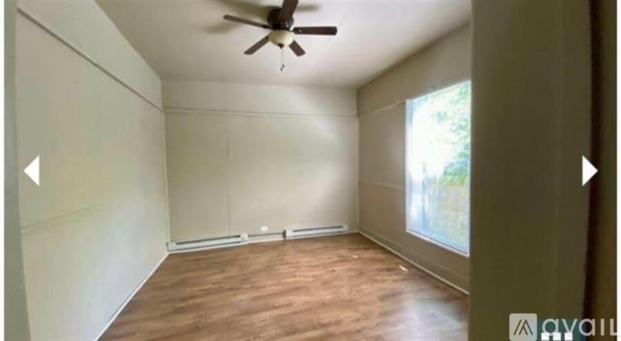 A room with a ceiling fan and wooden flooring.