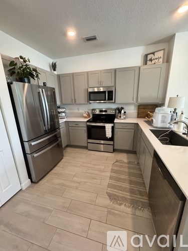 A kitchen with tile flooring and stainless steel appliances.