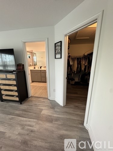 A room with a wooden floor and a white door leading to another room.