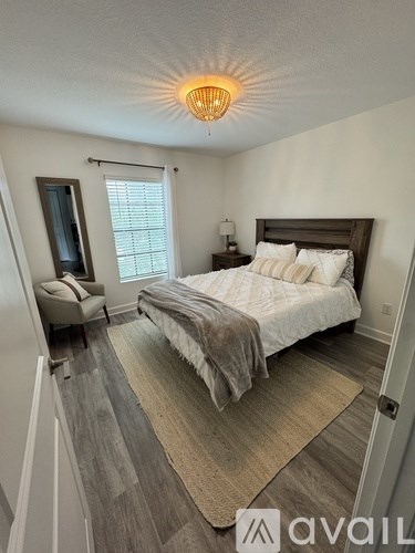 A bedroom with a bed, chair, and window.