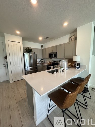 A kitchen with a white island and brown chairs.