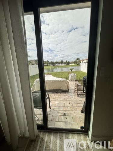 A patio with a table and chairs is visible through an open sliding glass door.