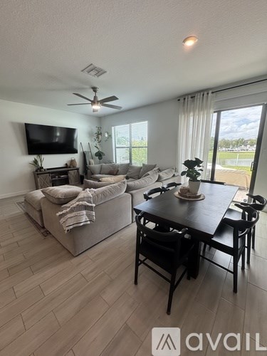 A living room with a grey couch, a black table, and a television mounted on the wall.