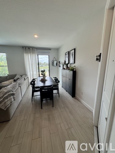 A dining table with chairs is in the middle of a room with a couch and a window.