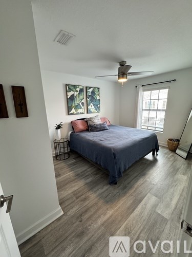 A bedroom with a bed, a ceiling fan, and a window.