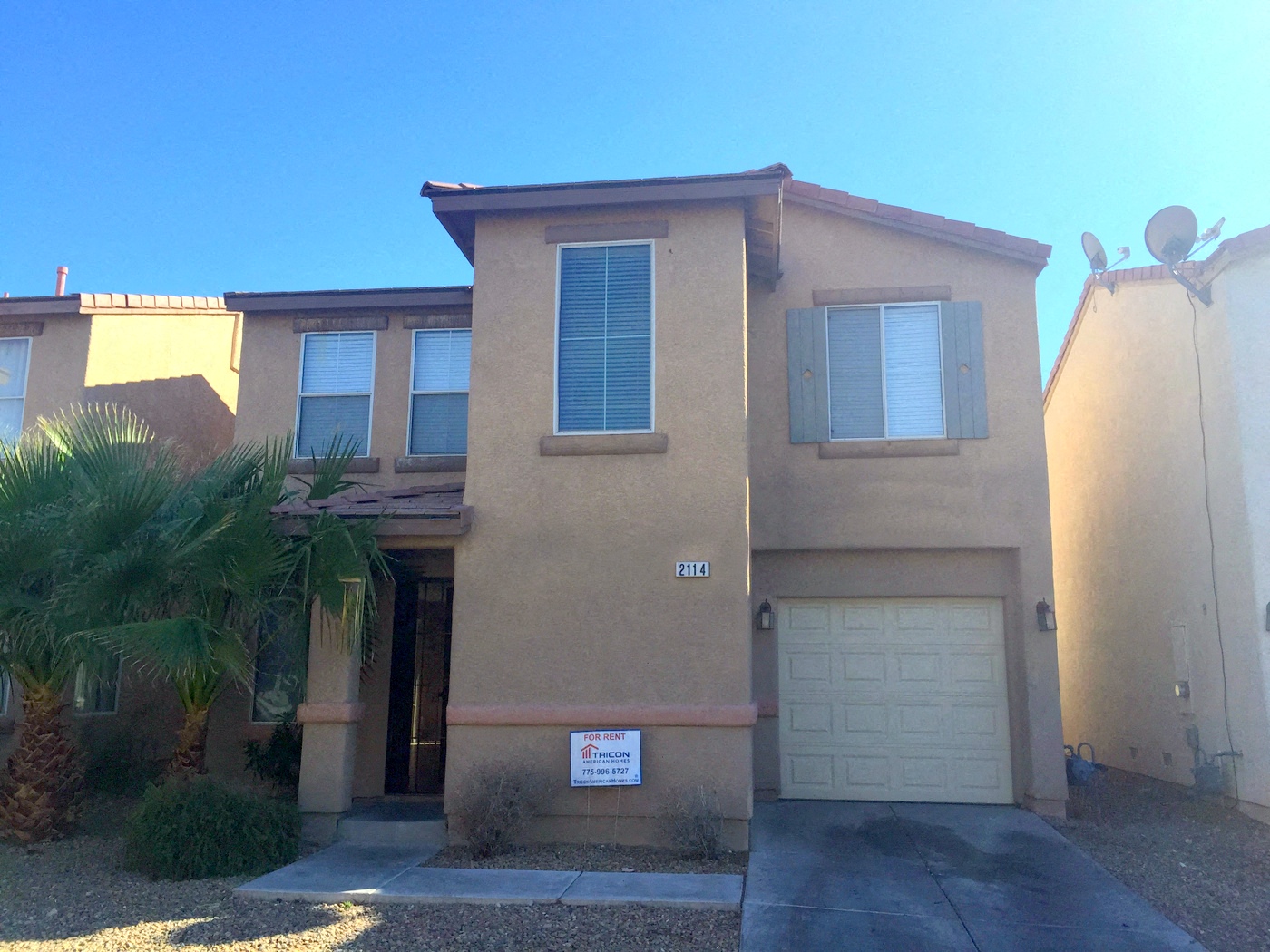 a house with a garage door and a palm tree