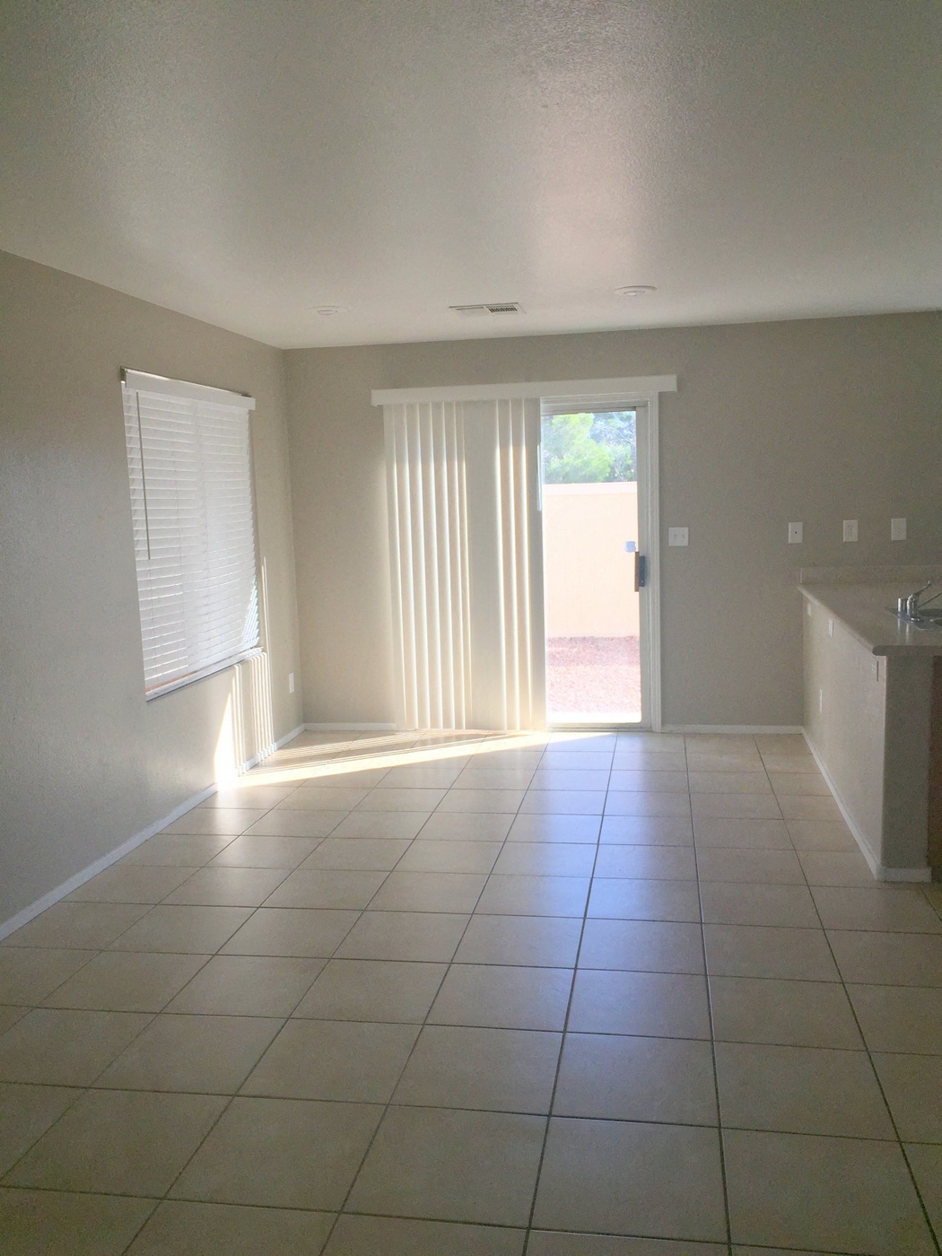 an empty living room with a tiled floor and a door to a patio