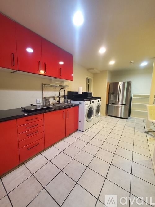 A kitchen with red cabinets and a black counter top.