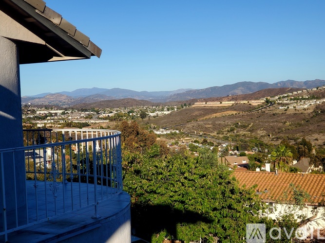 A balcony overlooks a valley with mountains in the distance.