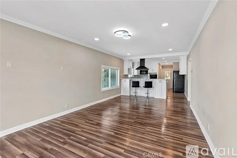 A spacious room with wooden flooring and a bar area.