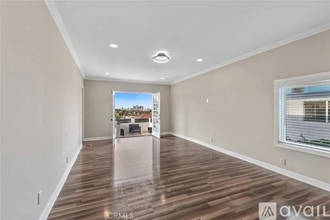 A spacious room with wooden flooring and a large window.