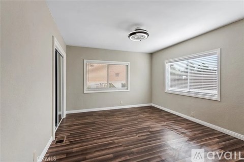 A room with wooden flooring and a window with blinds.