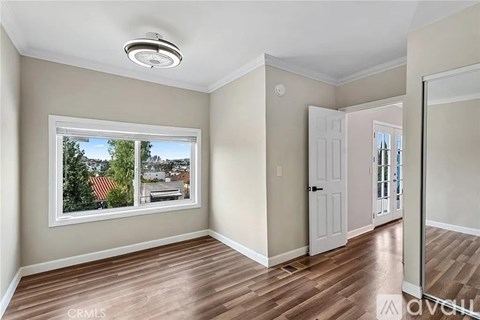 A room with wooden floors and a window showing a view of a street.