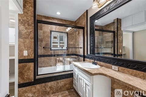 A bathroom with a sink, mirror, and tiled walls.