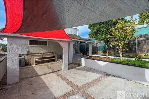 A patio area with a red awning and a white wall.