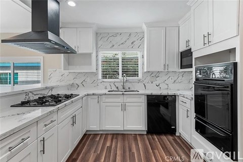 A kitchen with white cabinets and a marble backsplash.