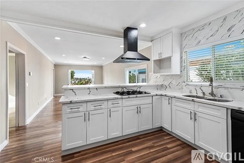 A modern kitchen with white cabinets and a black range hood.