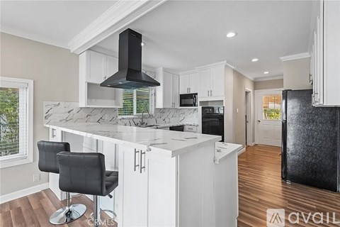 A kitchen with a marble countertop and a black hood.