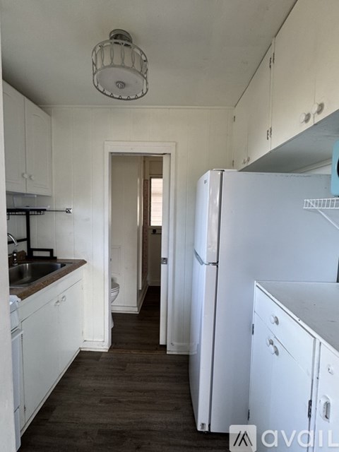 A kitchen with white cabinets and a white fridge.