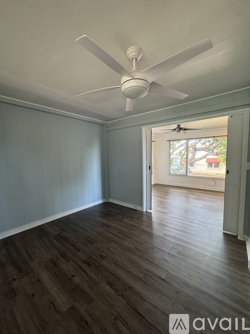 A room with a ceiling fan and wooden flooring.