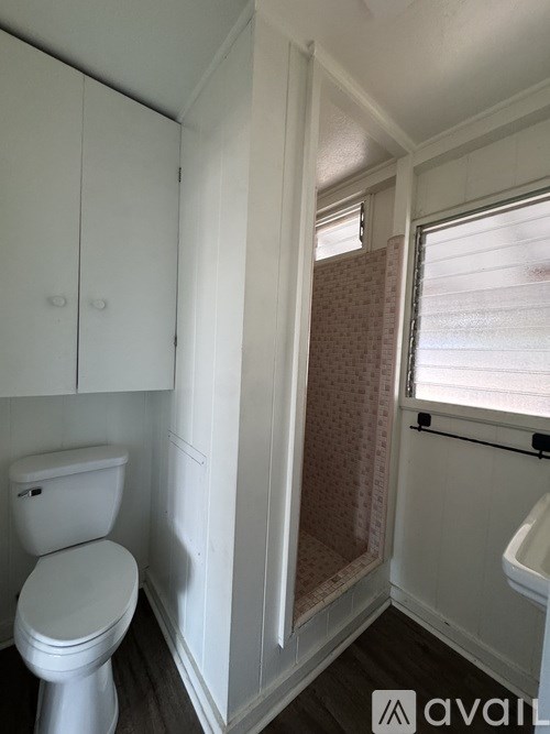 A white toilet in a small bathroom with a shower stall.